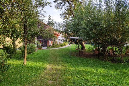 Stezka vede od pasivního domu kolem ohniště s posezením.