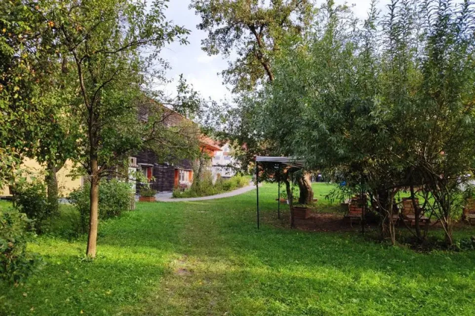 Stezka vede od pasivního domu kolem ohniště s posezením